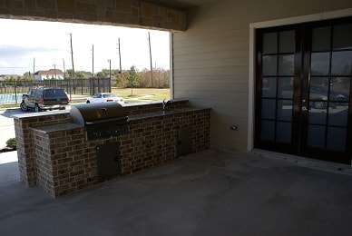 Covered outdoor patio with built-in brick grill and French doors
